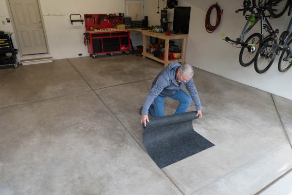 A man starting to unroll the product after sticking down an edge of the adhesive side.