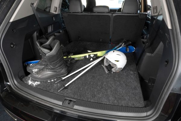 A variety of ski equipment in the trunk of an SUV sitting on the Cargo Liner keeping the trunk protected.