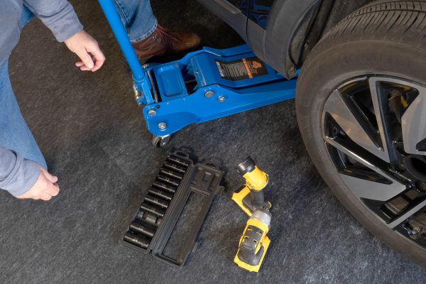 A person working on a car with a jack and tools all on top of the multi surface protector. This protects the garage floor from stains and messes.