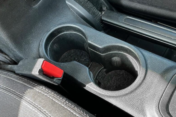 MatBoss cup holder liners on the bottom of 2 cup holders in a vehicle console.