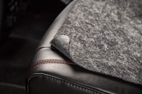 The seat shield with a corner lifted up to show the adhesive backing.